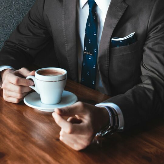 man holding cup filled with coffee on table